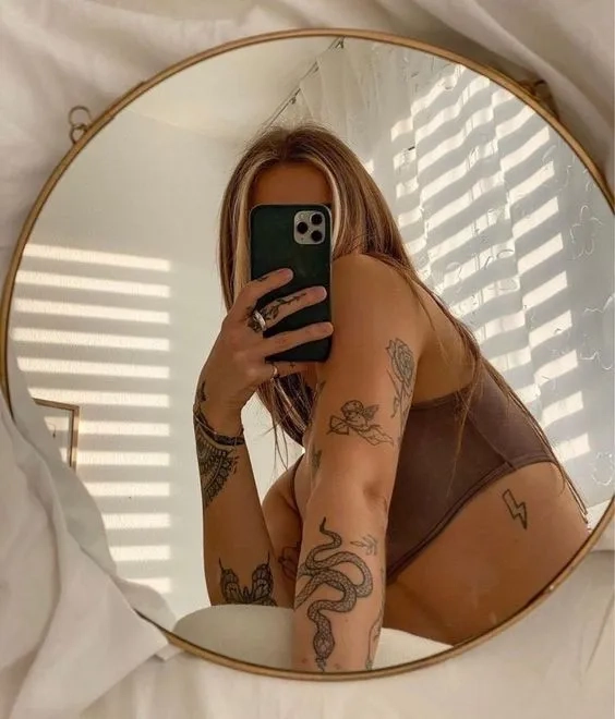 Femme tatouée prenant un selfie en se regardant dans le mirroir