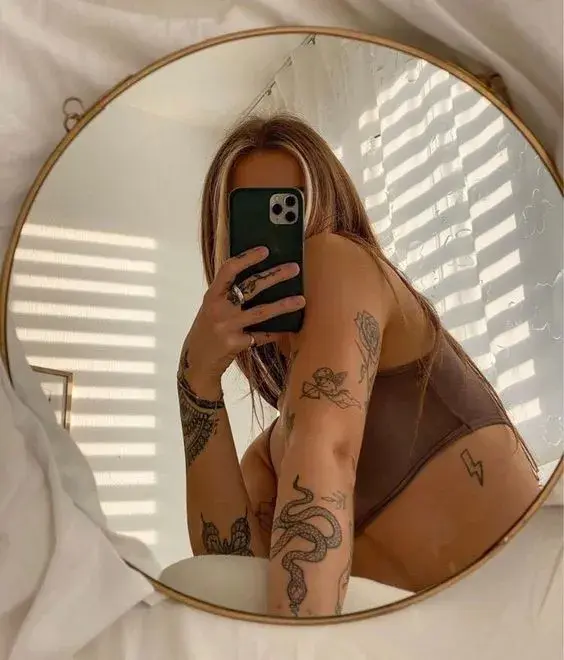 Une femme tatouée se prenant en photo en selfie dans un miroir