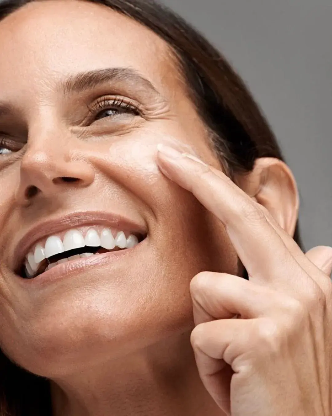 Femme souriante pointant une absence de rides